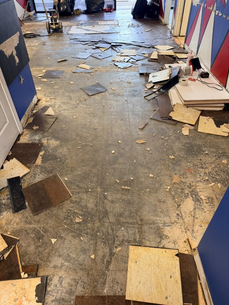 Store floor covered in torn-up tile and debris before Load Bros cleanup